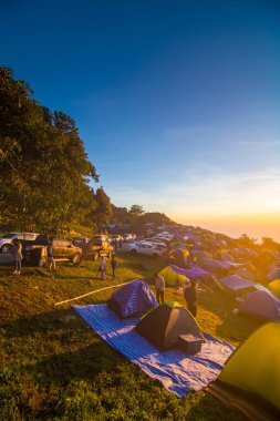 Tepede renkli bir kamp çadırı var. Gün doğumu dağda yürüyor.
