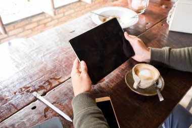 Adam, çalışma masası olan bir ahşap üzerinde dijital boş tablet ekranını gösterir