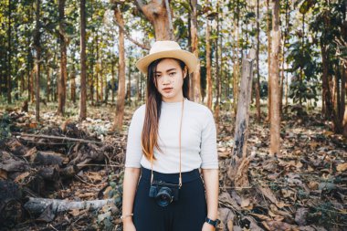 Aynasız bir kamerayla ormanda yürüyen hippi kız, Asyalı inek bir kadın.