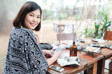 Kafede oturan akıllı telefonu kullanan bir iş kadını.