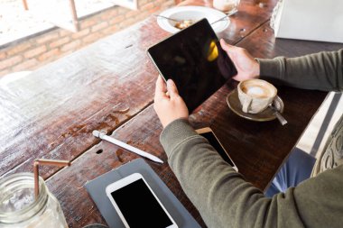 İnsan eli tablet boş ekranı ahşap masada sıcak latte ile kullanır, Arka görünüm eli kapat