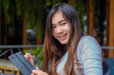 Kafede tablet kullanan Asyalı gülümseyen kız, iş kadını.