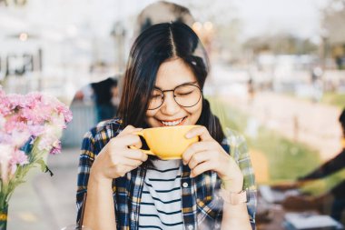 Bardaklı kadın modern kafede sıcak sütlü kahve içiyor.