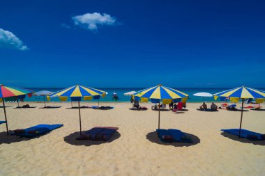 Deniz sahilinde plaj sandalyeleri ve şemsiyeler mavi gökyüzüne karşı, yaz tatili