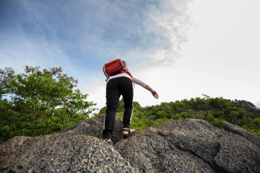 Güneşli bir günde dağın tepesinde yürüyüş yapan gezgin kampçı bir kadın. Güneşli bir günde dağın tepesinde yürüyor..