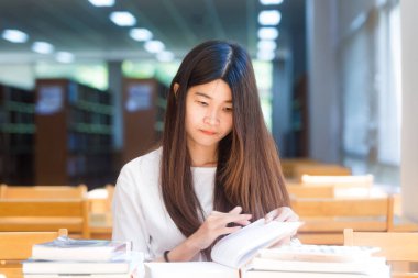 Hafif bir kitaplıktaki sınavı için kitap okuma penceresinden güzel bir öğrenci portresi