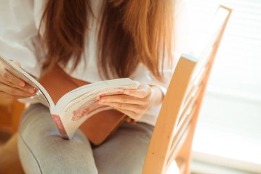 Kütüphane, iş eğitim kavramı okumak için kitap ahşap sandalye üzerinde oturan kadın.
