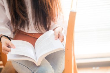 Kütüphane, iş eğitim kavramı okumak için kitap ahşap sandalye üzerinde oturan kadın.