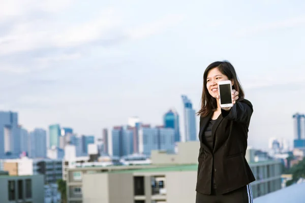 Business asian woman use of mobile phone and showing of screen bulding background