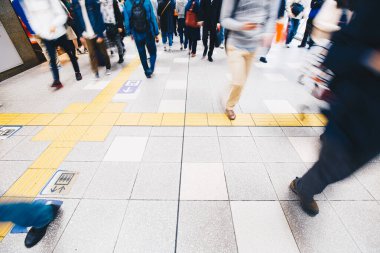 Osaka tren istasyonunun arka planında yürüyen bulanık yolcular