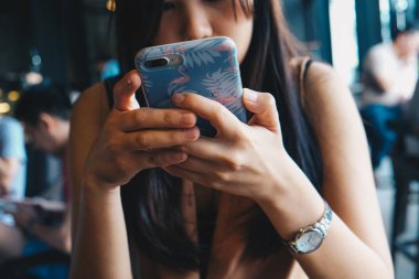 Kahve dükkanında oturan sıradan bir kadın her yerden internet üzerinden akıllı telefon bağlantısı kullanıyor.