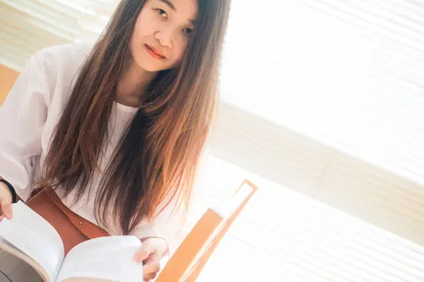 Feliz Asiático Estudiante Joven Mujer Pensando Con Libro Biblioteca Sentado —  Fotos de Stock