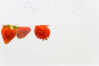 Beyaz arka planda suda taze çilek sıçraması