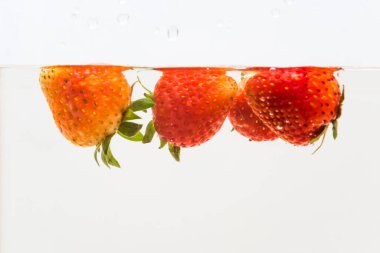 Beyaz arka planda suda taze çilek sıçraması