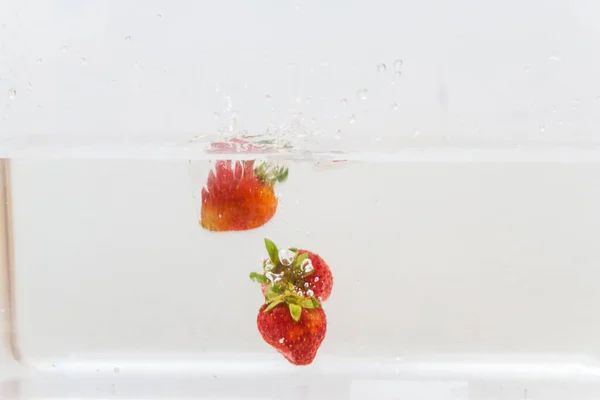 Strawberry vitamin fruit splash in water on white background