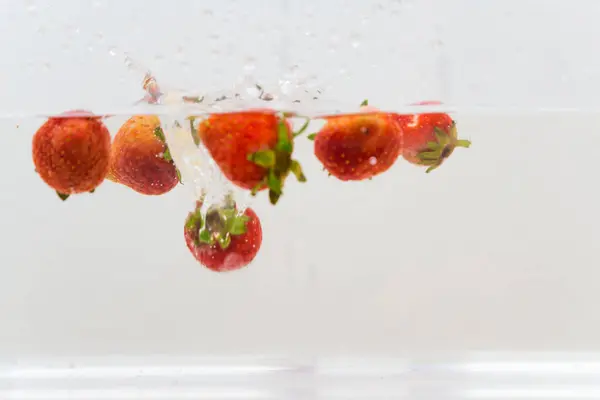 Strawberry vitamin fruit splash in water on white background