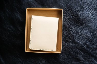 Siyah deri arka planda bitkisel bronzlaşmış deri cüzdan, işçilik objesi.