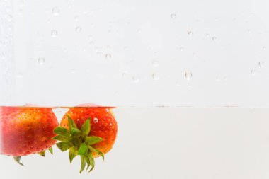 Beyaz zemin üzerinde temiz suda taze çilek meyvesi