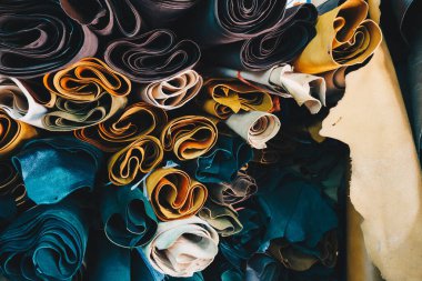 Rafta bir sürü renkli sığır derisi var. El işi atölyesinde, deri arka planda.