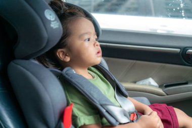 Bebek koltuğunda oturan mutlu anaokulu kızı.  