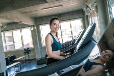 Güzel Asyalı kadın koşu yapıyor. Koşu bandında koşuyor. Spor salonunda.