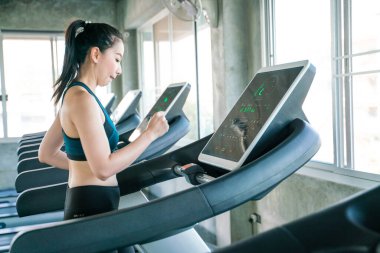 Güzel Asyalı kadın koşu yapıyor. Koşu bandında koşuyor. Spor salonunda.