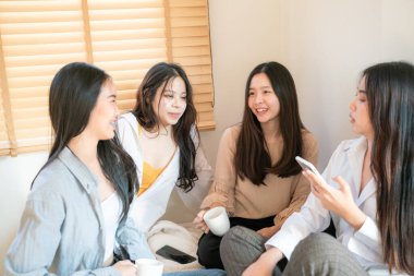 Asyalı güzel bir bayan arkadaş sıcak bir evde buluşuyor kahve içiyor, rahatlıyor, buluşuyor.