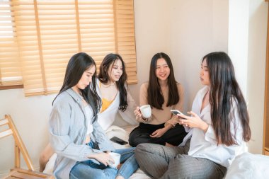 Asyalı güzel bir bayan arkadaş sıcak bir evde buluşuyor kahve içiyor, rahatlıyor, buluşuyor.