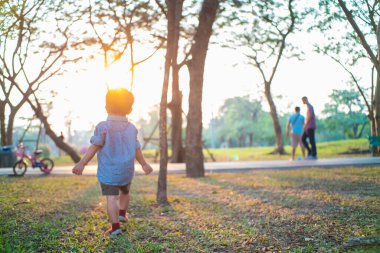 Neşeli çocuk Asyalı 2 yaşındaki çocuk şehir parkında oynuyor. Gün batımı sıcak hava aktivitesi.