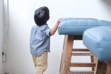 2 yaşında Asyalı bir çocuk kafe restoranında sandalye oynuyor.