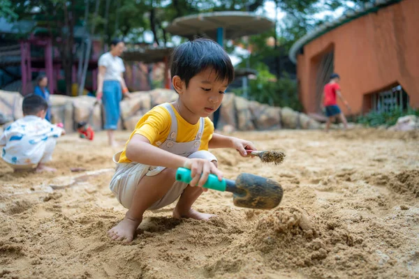 5 yaşındaki Asya anaokulu çocuğu kum havuzunda oyun parkında eğleniyor. Açık havada yaratıcı faaliyetler