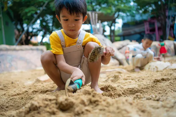 5 yaşındaki Asya anaokulu çocuğu kum havuzunda oyun parkında eğleniyor. Açık havada yaratıcı faaliyetler