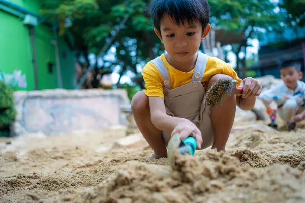 5 yaşındaki Asya anaokulu çocuğu kum havuzunda oyun parkında eğleniyor. Açık havada yaratıcı faaliyetler