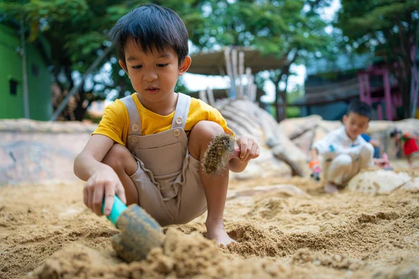 Asyalı çocuk. 5 yaşında. Kum havuzunda oyun oynuyor. Açık havada kreş aktiviteleri