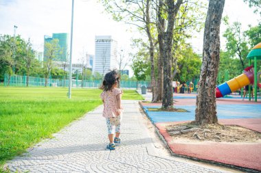 Yeşil çayır çimlerinde oynayan sevimli küçük kız şehir parkında mutlu Asyalı kız.