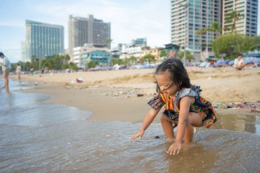 Mutlu küçük Asyalı kız yaz tatilinde şehir sahilinde kum oynuyor Pattaya Tayland