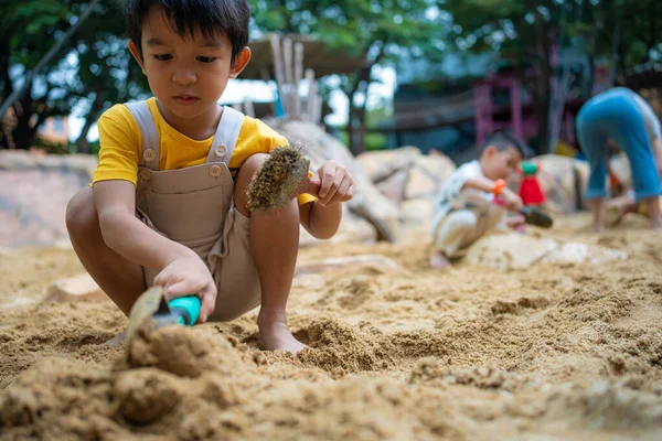 stock image Asian kid boy 5 year old enjoying play outdoor sandbox having fun on playground in sandpit. Outdoor creative kindergarten activities