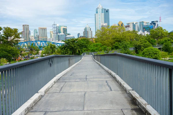 Asplalt, yeşil ağaç ormanı ve ofis binalarıyla şehir parkında yürüyüş yapıyor.  