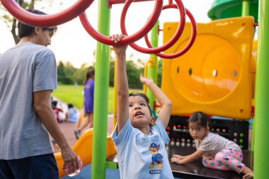 Anaokulundaki Asyalı çocuk şehir dışında oyun parkında eğleniyor iyi tatiller öğreniyor ve egzersiz yapıyor.