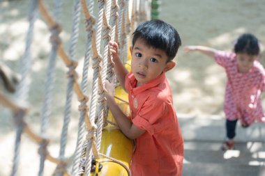 Anaokulundaki Asyalı çocuk şehir dışında oyun parkında eğleniyor iyi tatiller öğreniyor ve egzersiz yapıyor.