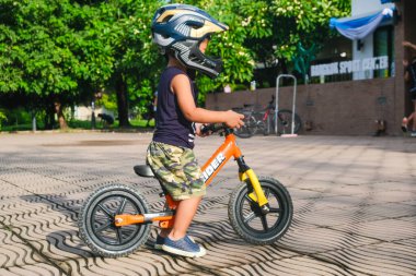 Okul öncesi Asyalı çocuk şehir parkında bisiklet sürme alıştırması yapıyor.