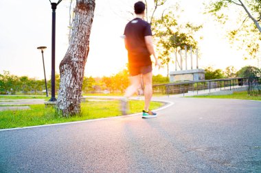 Asfalt yol parkı koşu yolu üzerinde gün batımı ışığı ve doğa arka planıyla yeşil çayır otları ile yol