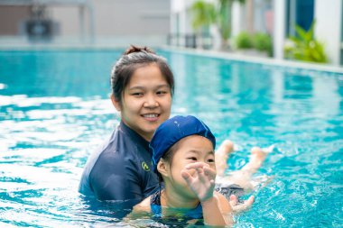 Güzel kızıyla yüzen Asyalı bir anne açık havada mutlu bir aile.