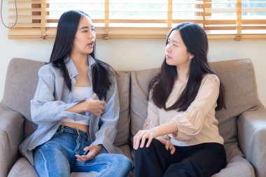 Güzel, güzel Asyalı iş kadını arkadaşın koltukta oturup sohbet ediyor.