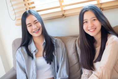 Güzel, güzel Asyalı iş kadını arkadaşın koltukta oturup sohbet ediyor.