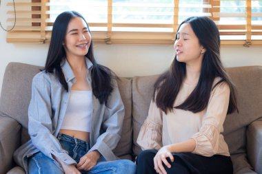 Güzel, güzel Asyalı iş kadını arkadaşın koltukta oturup sohbet ediyor.