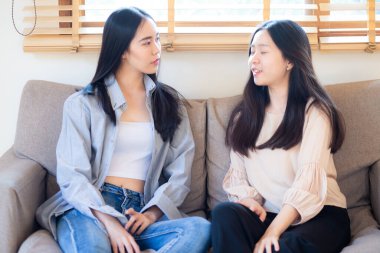 Güzel, güzel Asyalı iş kadını arkadaşın koltukta oturup sohbet ediyor.