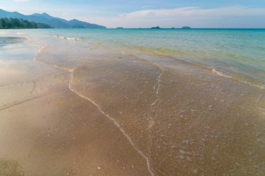 Deniz kıyısı dalgaları berrak turkuaz deniz suyu pürüzsüz kum mavisi gökyüzü bulutlu yaz tatili arka planı