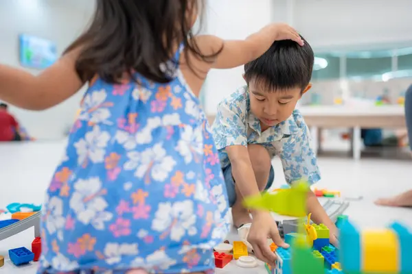 Adorable kindergarten kid asian boy and girl enjoying play colorful toy block indoor education