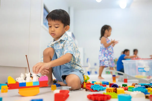 Adorable kindergarten kid asian boy and girl enjoying play colorful toy block indoor education